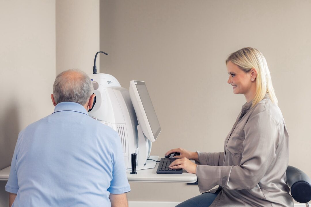 Patient wird am OCT von einer Mitarbeiterin untersucht.