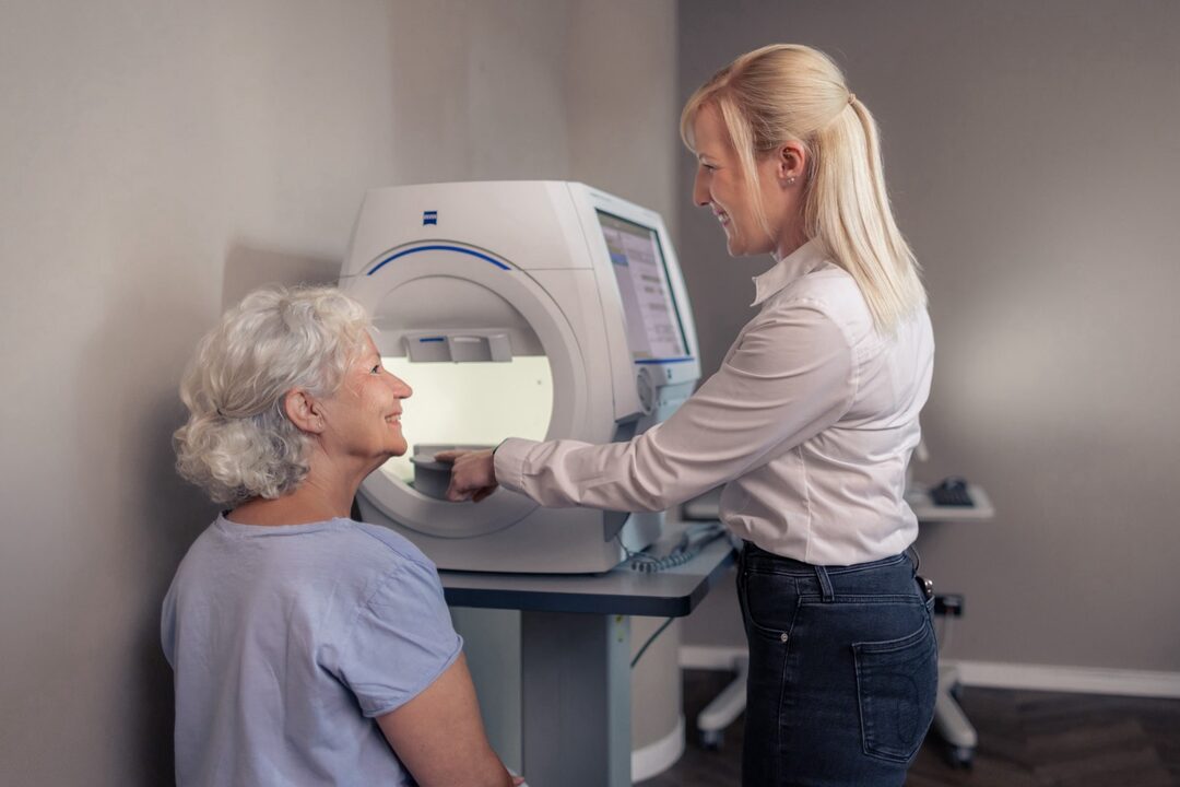 Perimetrie: Die Mitarbeiterin zeigt der Patientin das Vorgehen.