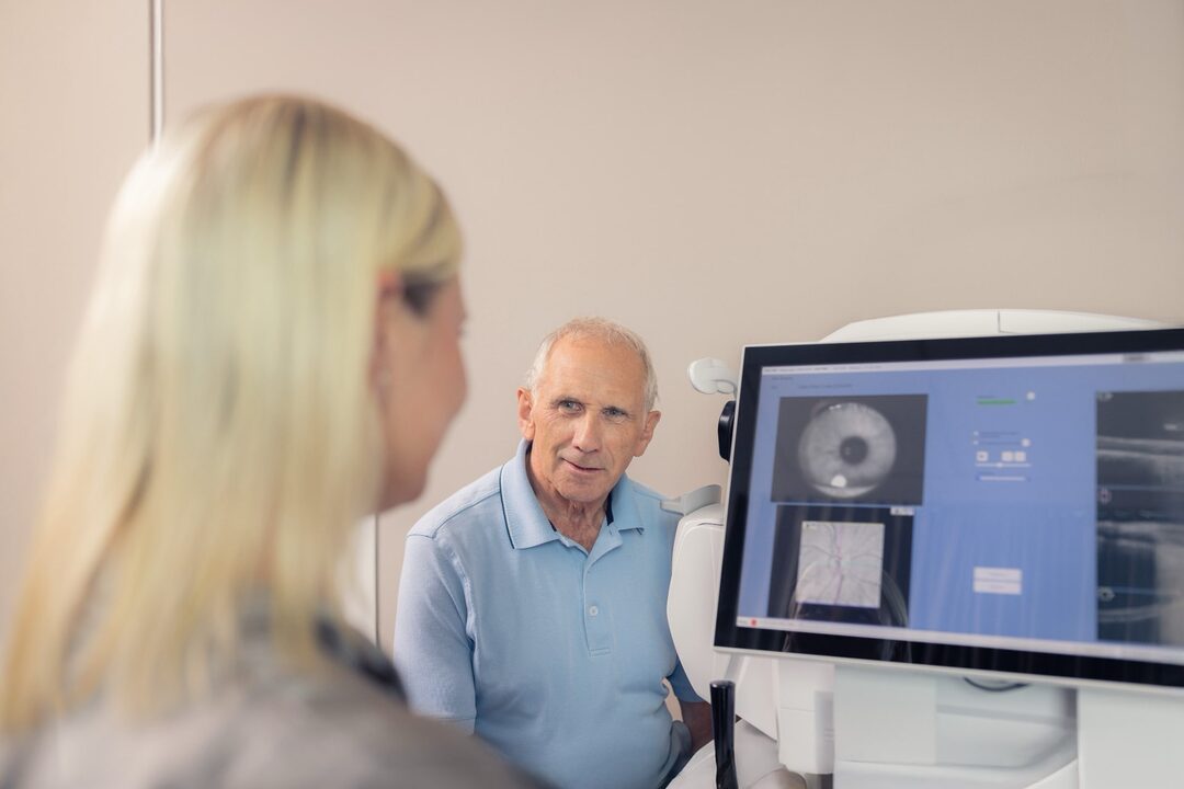 Mitarbeiterin spricht am OCT mit dem Patienten.