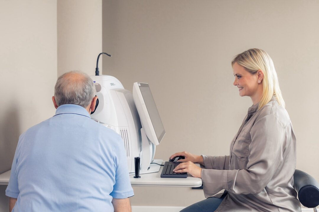 Patient wird am OCT von einer Mitarbeiterin untersucht.