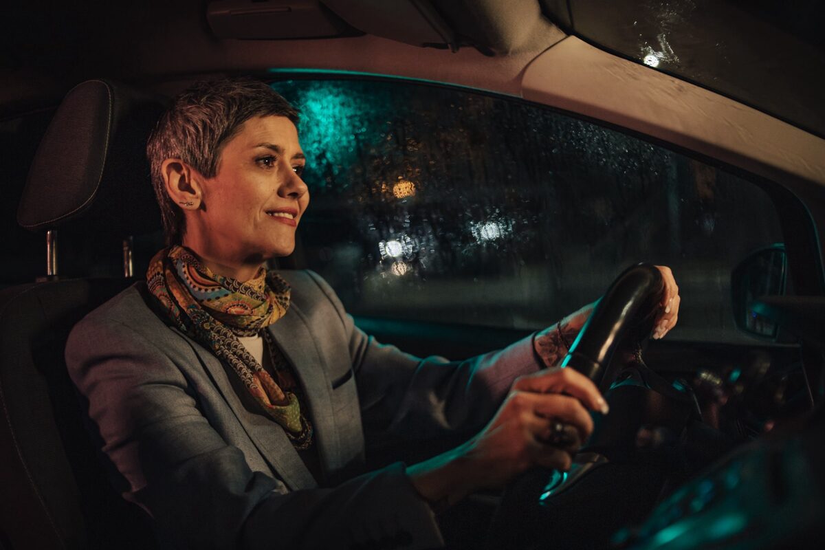 Frau mittleren Alters fährt Auto in der Dunkelheit.